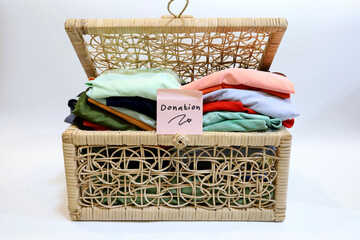 Used clothes in a rattan basket isolated on a white background with donation writing. the concept of donating used goods, charity and protecting the environment by utilizing used goods.