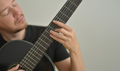 A man playing the guitar. Hands on the strings. Close-up portrait. Chord selection. Musician playing electric guitar. Banner wallpaper with copy space at the white background