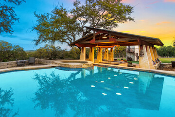 Relaxing evening by the serene pool area with a spacious deck and vibrant sunset in the background