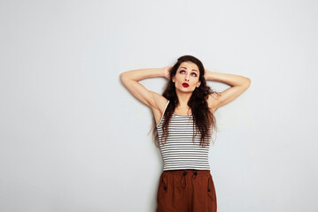 Beautiful positive fun makeup woman in stripped casual t- shirt looking up and thinking on empty copy space studio