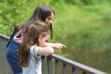 Two little preschool girls playing near a pond. Concept of children's fun outdoors