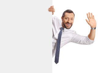 Cheerful man waving behind a blank white panel