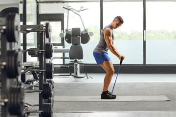 Fototapeta premium Guy exercising with a resistance band on a mat at a gym