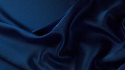 Obraz premium A close-up shot of deep blue fabric with soft, natural folds and wrinkles, showcasing its smooth texture and rich color. Ideal for fashion, textiles, or backgrounds