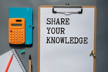 Notebook with SHARE YOUR KNOWLEDGE word with office tools on white table.