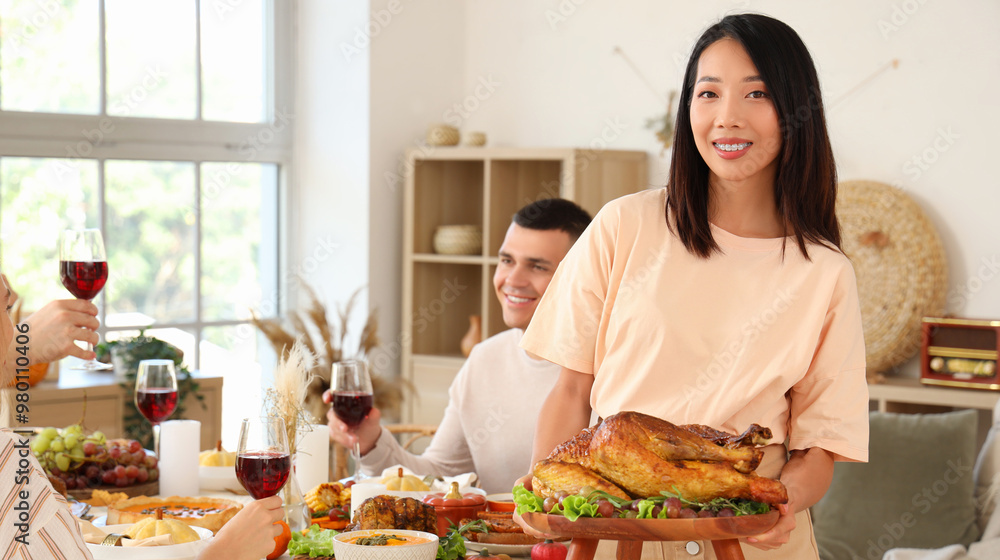 Poster Young Asian woman with turkey having dinner on Thanksgiving Day