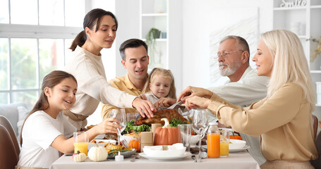 Happy family having dinner at festive table on Thanksgiving Day