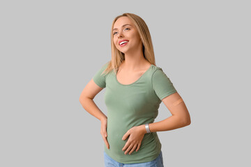 Young pregnant woman after vaccination on light background