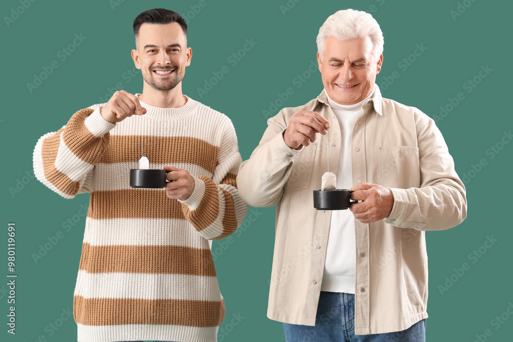 Wall mural young man with his father dipping tea bags into cups on green background