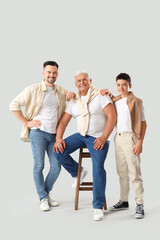 Fototapeta premium Teenage boy with his dad and grandfather on light background