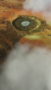 Aerial view flying above the clouds of the Wolfe Creek Meteorite Crater in Australia