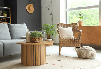 Sofa, wicker armchair and round wooden table in interior of living room
