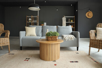 Sofa, wicker armchairs and round wooden table in interior of living room