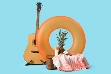 Inflatable ring, guitar and suitcase with beach accessories on blue background. Travel concept