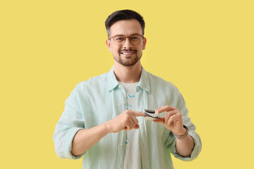 Young man with pulse oximeter on yellow background