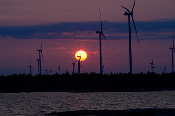 green energy: wind turbines at Henvey Inlet First Nation  in silhoutte with the sun rising behind...