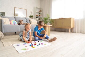 Little children sculpting from plasticine on floor at home