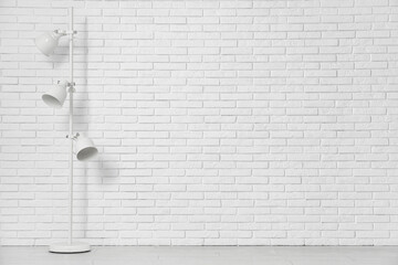 Floor lamp near white brick wall in room