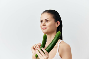 Woman holding cucumbers with a neutral background, healthy lifestyle concept, freshness, natural...