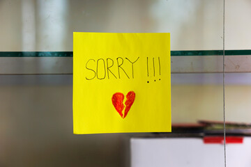 A heartfelt note on a yellow sticky note expresses deep remorse with a broken heart drawing.