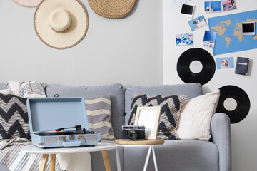 Interior of stylish living room with grey sofa, record player and mood board