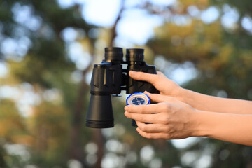 Fototapeta premium Woman with compass and binoculars in forest, closeup