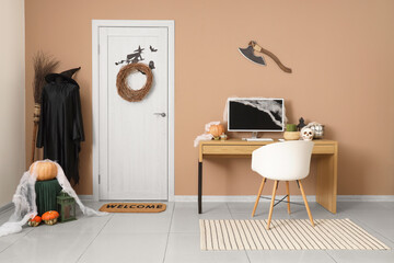 Interior of office decorated for Halloween with door, witch costume and workplace