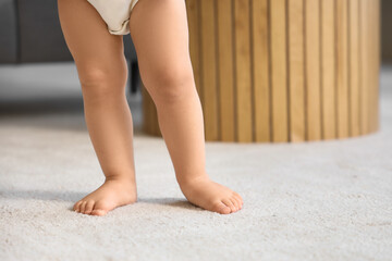 Cute baby girl learning to walk at home, closeup