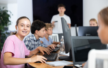 Fototapeta premium Happy underage girl engaged in IT training during computer courses for children