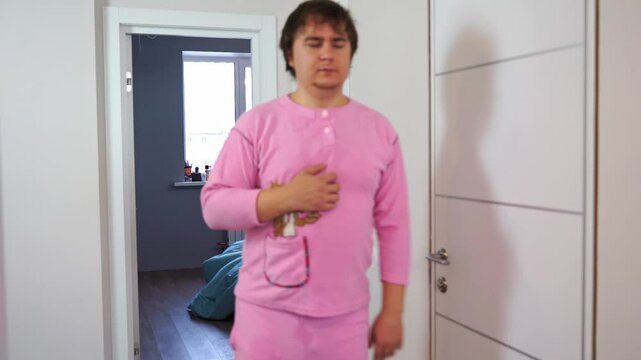 Sleepy, tired, disheveled man in pink pajamas walks staggering with eyes closed, no energy, vitamin deficiency, burnout Wake up in morning sluggish and without energy unbalanced diet, lack of activity