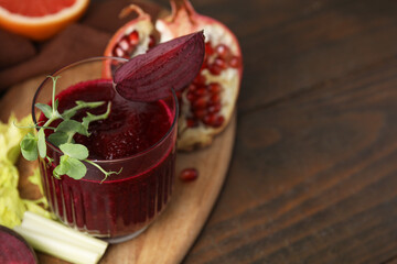 Tasty beetroot smoothie with microgreens in glass, fresh vegetables and fruits on wooden table, closeup. Vegan drink