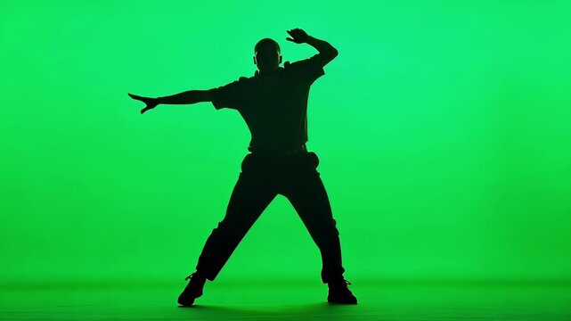 Young man dancing gracefully in a photography studio with a vibrant green screen background, showcasing modern dance styles like hip hop and breakdance