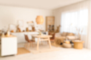 Blurred view of kitchen decorated for Halloween with white counters, sofa and dining table