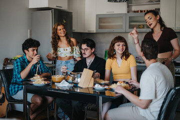 A group of young friends laughing and dining together around a table in a cozy kitchen setting, enjoying food and conversation.