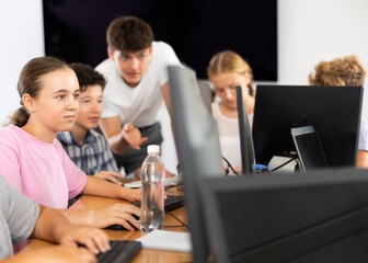 Fototapeta premium Concerned preteen girl working with computer programs with interest in training room