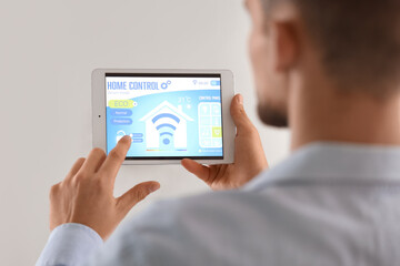 Young man using smart home control panel in room, closeup