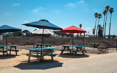 Outdoor Restaurant Dining Area With Colorful Umbrellas And Picnic Tables Under Clear Sky on a Sunny summer day near the coast in Southern California