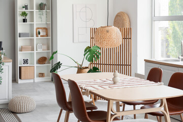 Interior of light kitchen with dining table, shelf unit and plants