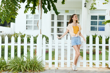 Summer fashion photography, woman in casual outfit near white picket fence, sunlight, green grass,...