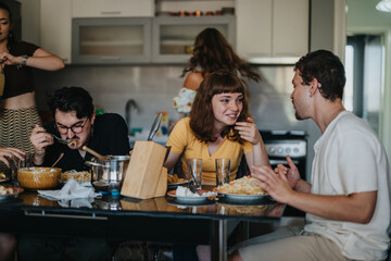 A group of friends share a casual meal in a contemporary kitchen, enjoying food and conversation, creating a friendly and relaxed atmosphere.