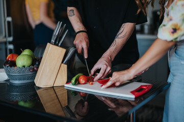 A couple enjoying quality time together while slicing fresh vegetables in a modern kitchen, symbolizing healthy living and teamwork.