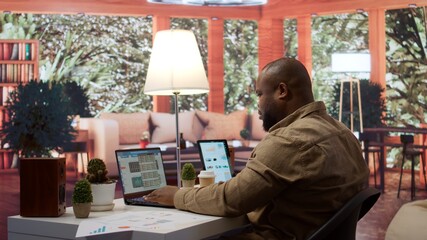 Sales analyst verifying infographics plan for accounting balance, works from home to achieve business strategies and goals. Expert studying market dynamics and big data on reports. Camera B.