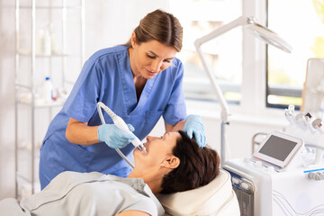 Woman doctor doing a facial deep hydration procedure on elderly female pacient in aesthetic...