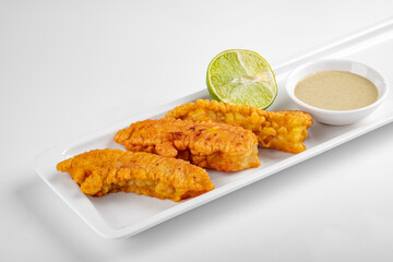 Fish fillets fried in breadcrumbs and served in a white plate on
