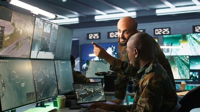 Army colleagues looking at screens in command center housing operational missile defense system designed to intercept ballistic rockets. Experts using tracking gear and radar systems, camera B