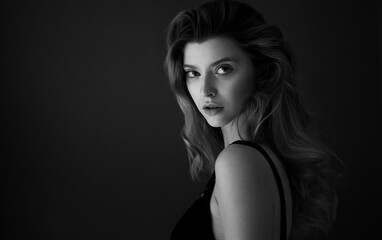 Naklejka premium Young pretty sexy woman with long wavy hair. Studio portrait of model girl with curly hair. Haircare and skincare beauty products, shampoo and lotion. Spa and wellness. Selective focus.