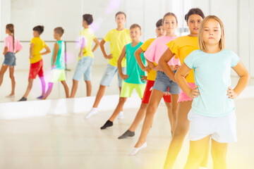 Fototapeta premium Group of positive children rehearsing movements of ballet in classroom