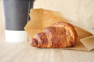 Indulge in a Fresh Croissant and a Cup of Coffee Beautifully Arranged on a Wooden Table