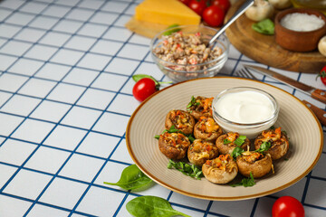 Stuffed mushrooms on plate, sauce and ingredients on light background, space for text