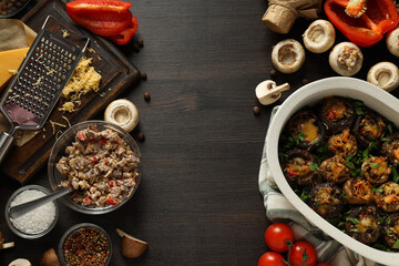 Stuffed mushrooms, kitchen board and ingredients on wooden background, space for text